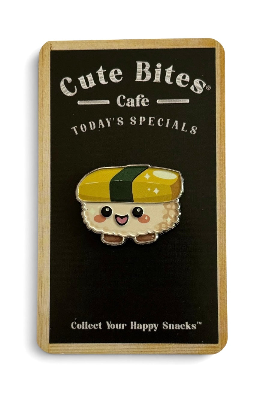 A cute sunny egg sushi snack enamel pin displayed on a wooden sign that reads 'Cute Bites Cafe' and 'Collect Your Happy Snacks'. The pin features a smiling maki wrap sushi character with a yellow and green top, set against a black card with a light wood border.
Copyright © Cute Bites® All rights reserved.